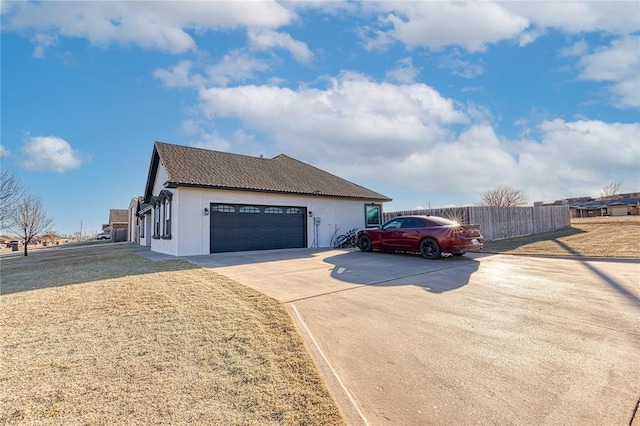 view of front of house with an attached garage, fence, concrete driveway, stucco siding, and a front yard