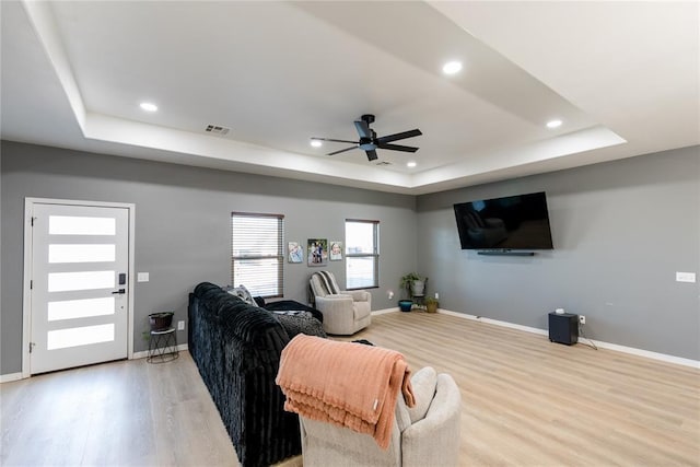 living area featuring light wood finished floors, recessed lighting, a raised ceiling, visible vents, and baseboards