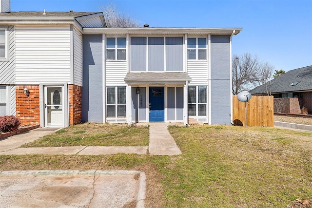 view of front of home with brick siding, a front yard, and fence