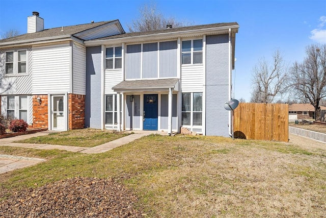 view of front of house with a chimney, fence, a front lawn, and brick siding