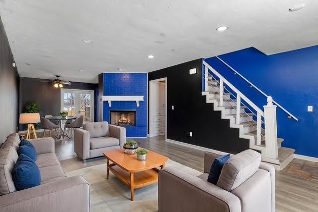 living room with a large fireplace, light wood finished floors, stairway, and baseboards