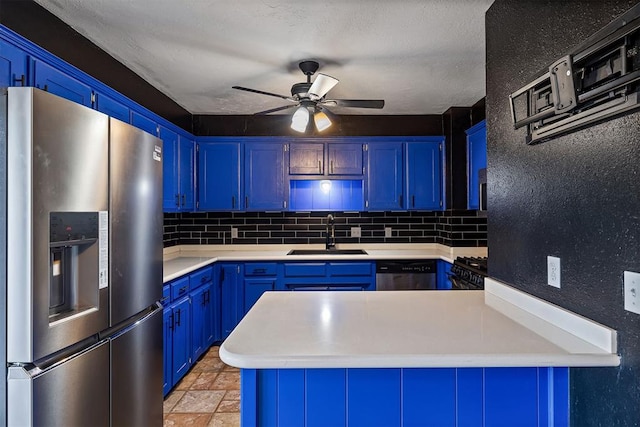 kitchen with stainless steel appliances, a peninsula, a sink, light countertops, and blue cabinetry