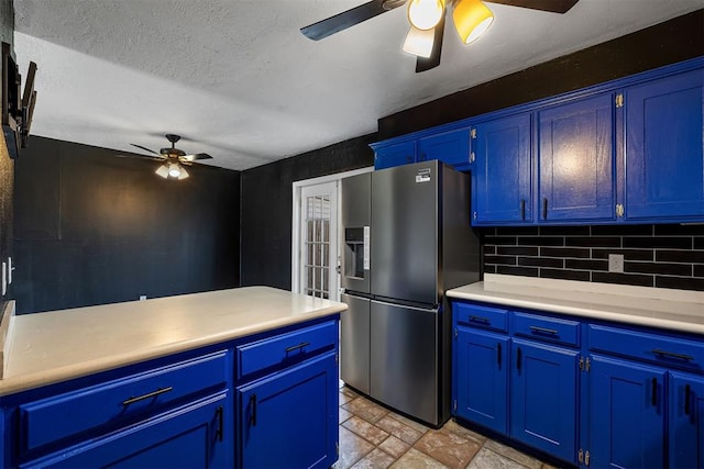 kitchen featuring blue cabinets, stone finish floor, light countertops, and stainless steel fridge with ice dispenser