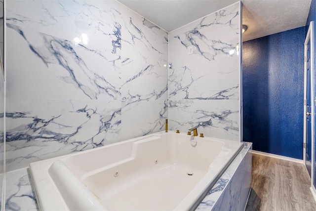 full bathroom with a textured ceiling, a tub with jets, and wood finished floors