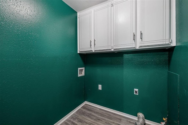 laundry area with wood finished floors, hookup for a washing machine, cabinet space, and baseboards