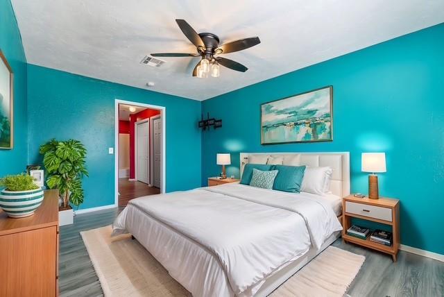 bedroom featuring visible vents, wood finished floors, a ceiling fan, and baseboards