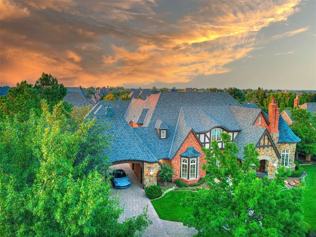 view of front of property with driveway, stone siding, and a chimney