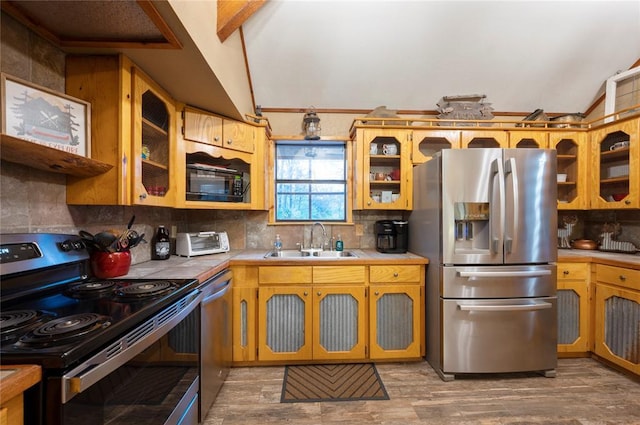 kitchen featuring a sink, vaulted ceiling, appliances with stainless steel finishes, tile counters, and tasteful backsplash