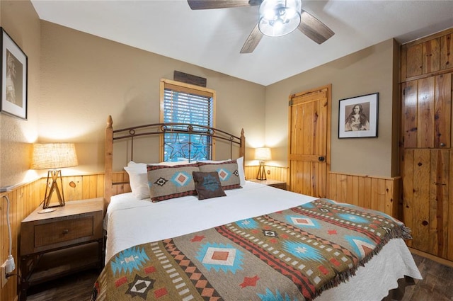 bedroom featuring a wainscoted wall, a ceiling fan, wood finished floors, and wood walls