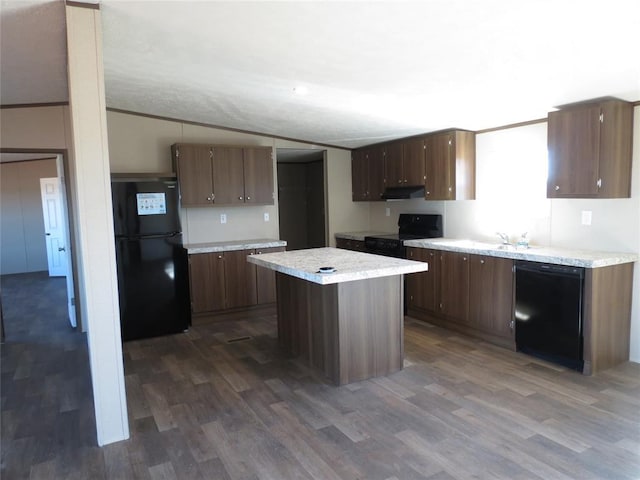 kitchen featuring lofted ceiling, black appliances, light countertops, and dark wood-type flooring