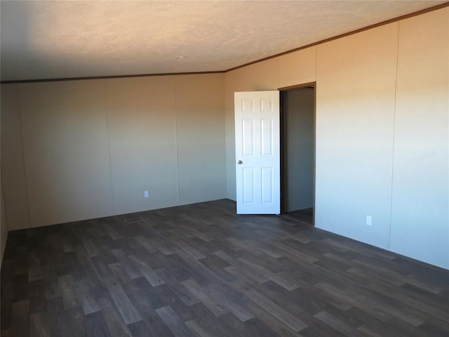 empty room with a textured ceiling, ornamental molding, and dark wood-type flooring