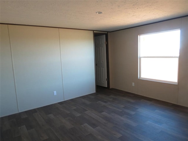 spare room featuring a textured ceiling and dark wood finished floors