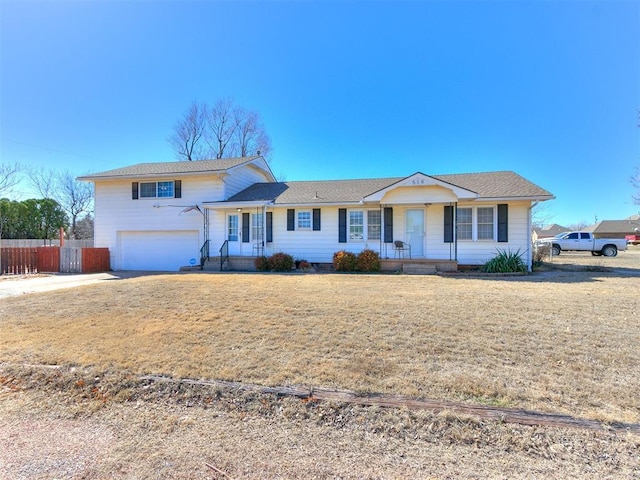 split level home featuring a front lawn, fence, and an attached garage