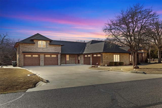 view of front of home with driveway, an attached garage, and a shingled roof