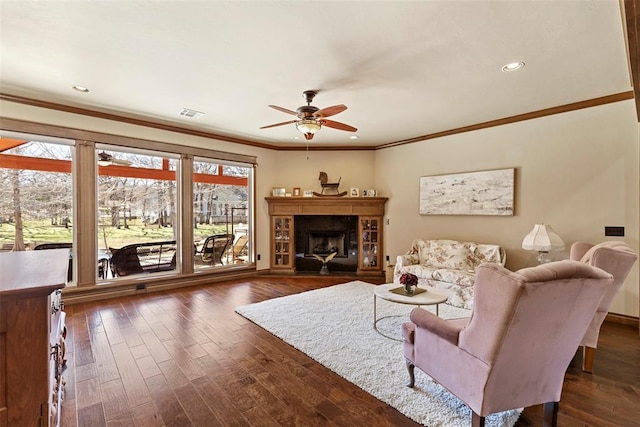 living room featuring ceiling fan, a fireplace, visible vents, and dark wood-style flooring