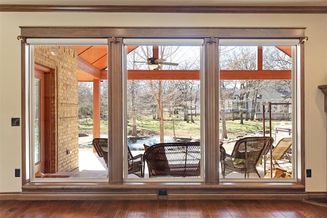 doorway with hardwood / wood-style flooring, a ceiling fan, and crown molding