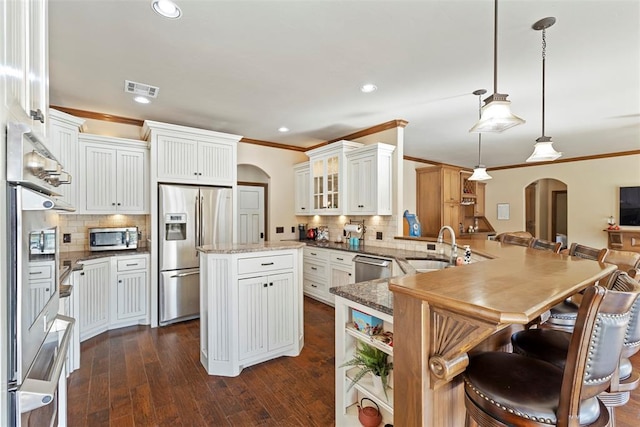 kitchen with visible vents, arched walkways, appliances with stainless steel finishes, a peninsula, and a sink