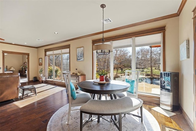 dining space with wood-type flooring, visible vents, crown molding, and baseboards