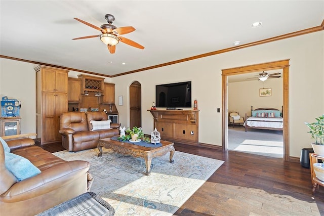 living room featuring baseboards, crown molding, arched walkways, and wood finished floors