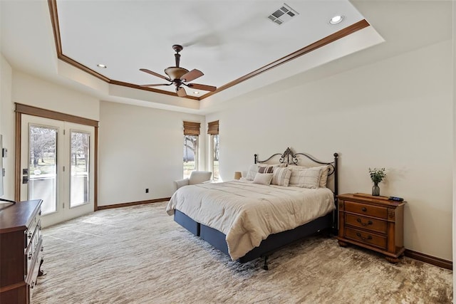 carpeted bedroom with a tray ceiling, visible vents, and multiple windows