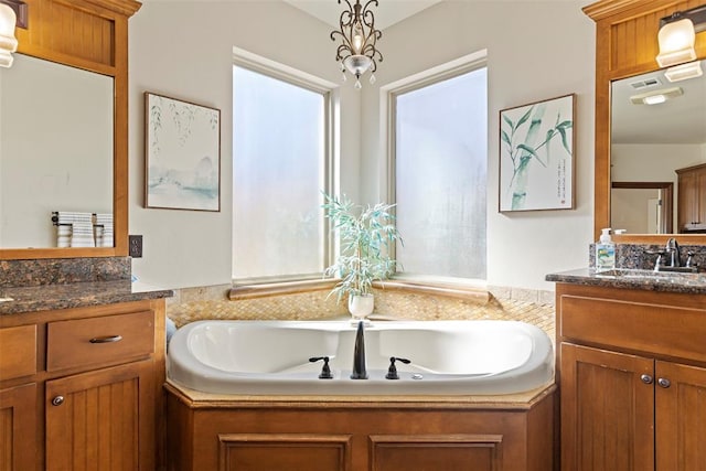 full bathroom with a garden tub, two vanities, and a sink