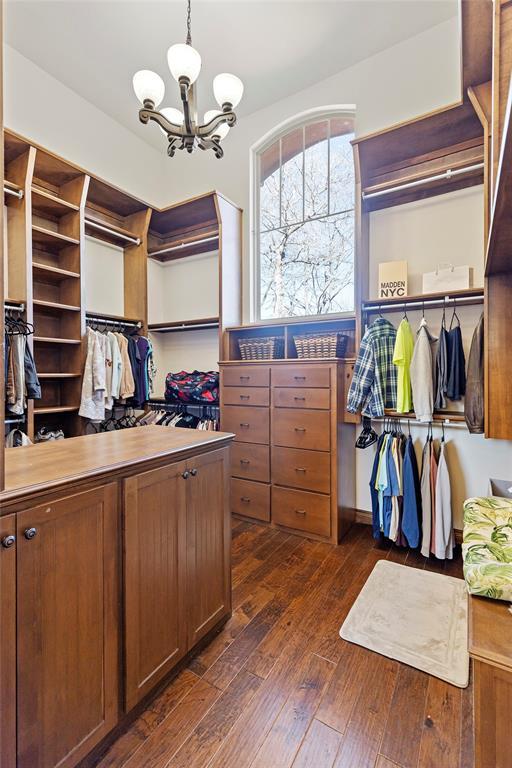 spacious closet with dark wood-style flooring and a notable chandelier