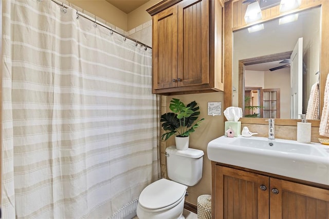 bathroom with ceiling fan, curtained shower, vanity, and toilet