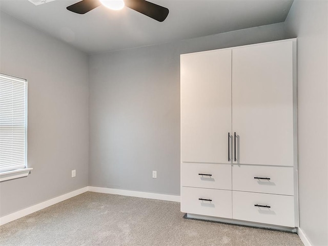 unfurnished bedroom featuring a ceiling fan, light colored carpet, and baseboards