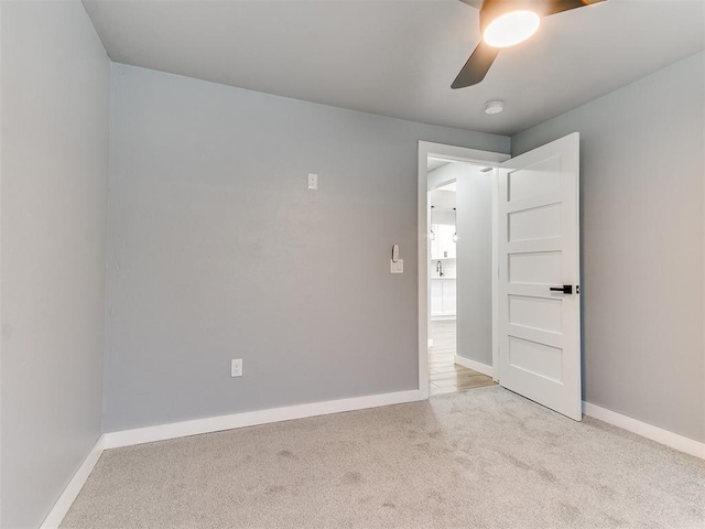 carpeted empty room with ceiling fan and baseboards