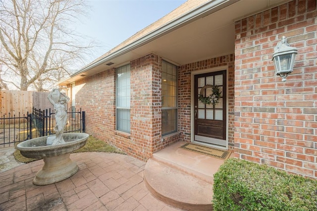 entrance to property featuring brick siding and fence