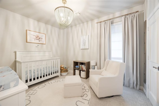 bedroom with carpet flooring, visible vents, a crib, and an inviting chandelier