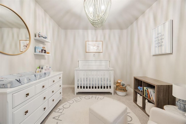 bedroom with light carpet, a nursery area, and an inviting chandelier