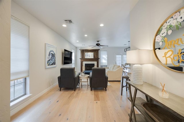 living room featuring a ceiling fan, visible vents, light wood finished floors, recessed lighting, and a fireplace