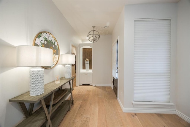 interior space with a chandelier, light wood-type flooring, and baseboards