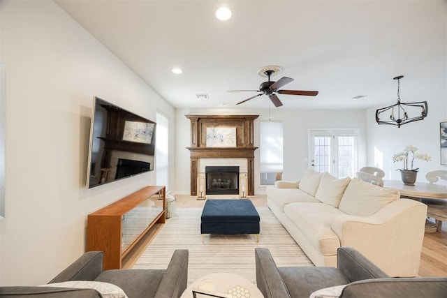 living area featuring visible vents, light wood-style flooring, a ceiling fan, recessed lighting, and a large fireplace