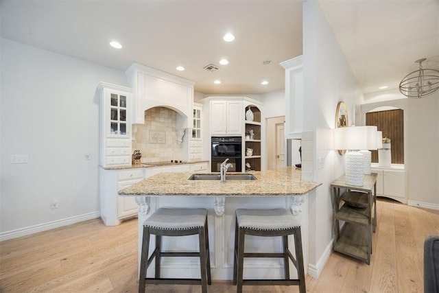 kitchen with visible vents, black appliances, open shelves, light stone counters, and a kitchen breakfast bar