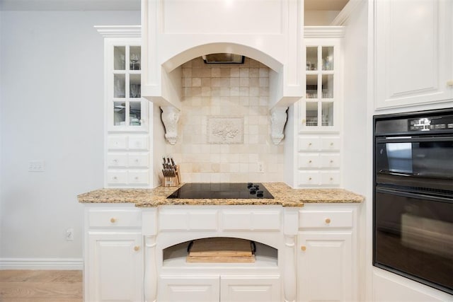 kitchen with black appliances, white cabinets, light stone countertops, and tasteful backsplash