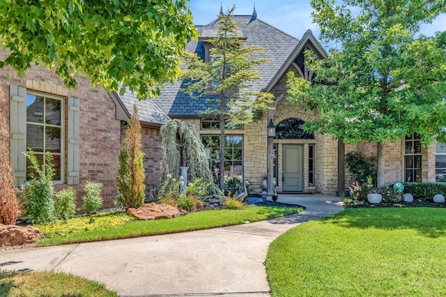 tudor-style house with stone siding, brick siding, and a front yard