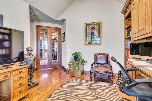 office with vaulted ceiling, wood finished floors, french doors, and visible vents