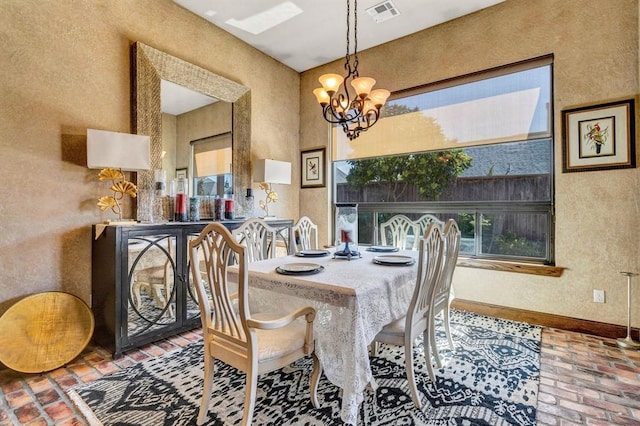 dining space featuring a notable chandelier, visible vents, baseboards, and brick floor