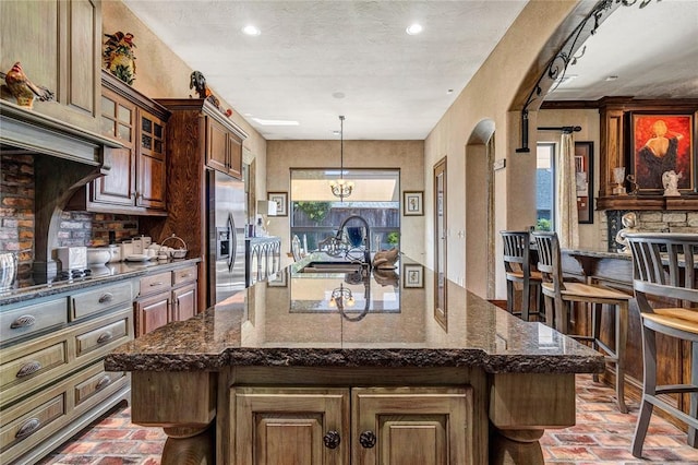 kitchen with brick floor, tasteful backsplash, stainless steel fridge with ice dispenser, and a sink