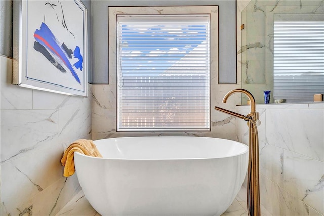 full bath with a healthy amount of sunlight, a freestanding bath, and tile walls