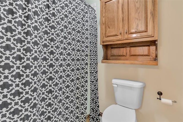 bathroom with curtained shower and toilet