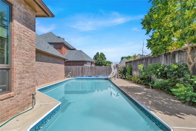 view of swimming pool with a fenced in pool, a water slide, and a fenced backyard