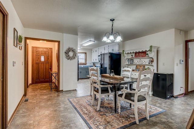 dining space featuring visible vents, a notable chandelier, and baseboards