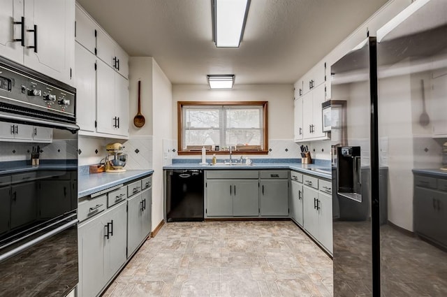 kitchen with a sink, white cabinetry, gray cabinets, backsplash, and black appliances