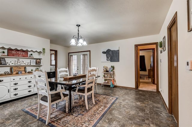 dining space featuring stone finish flooring, french doors, an inviting chandelier, and baseboards