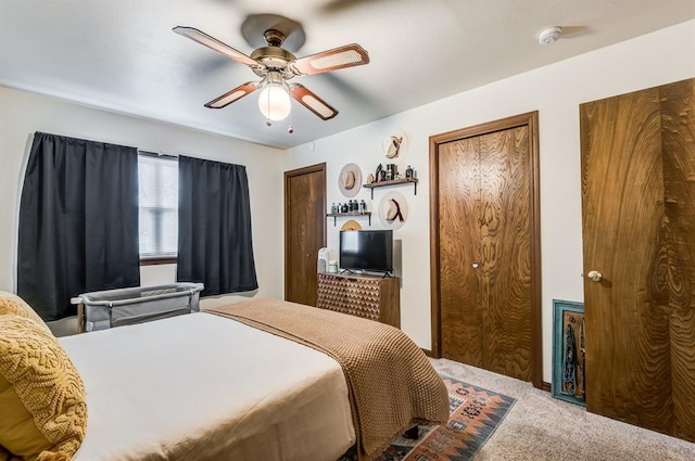 bedroom featuring multiple closets, carpet flooring, and a ceiling fan