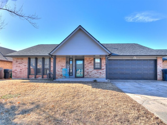 ranch-style home featuring concrete driveway, roof with shingles, an attached garage, a front lawn, and brick siding