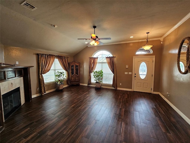 foyer with dark wood-style floors, a tile fireplace, visible vents, and baseboards